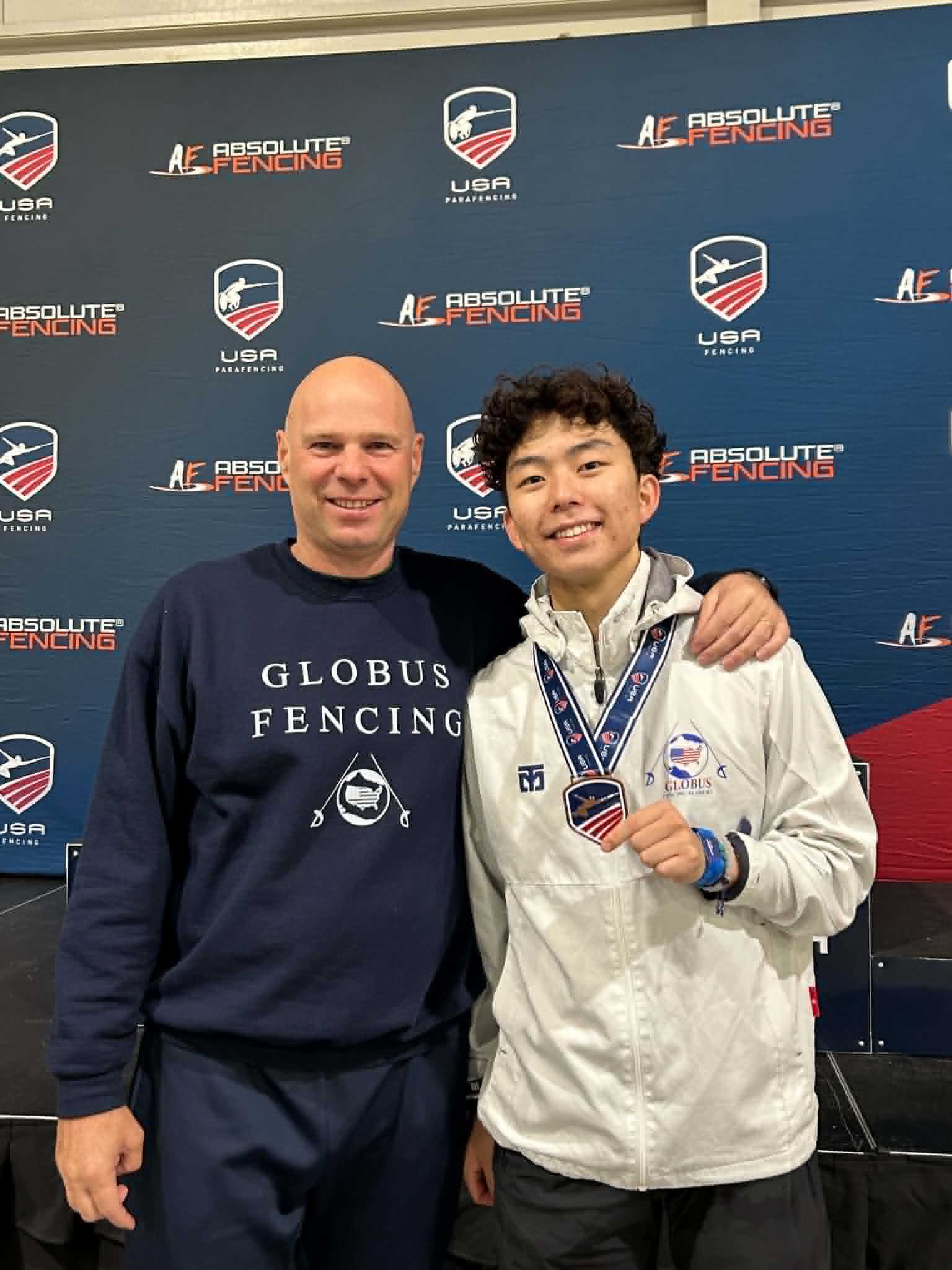Meester Paul Corteyn met een medaillewinnaar voor de backdrop van USA Fencing